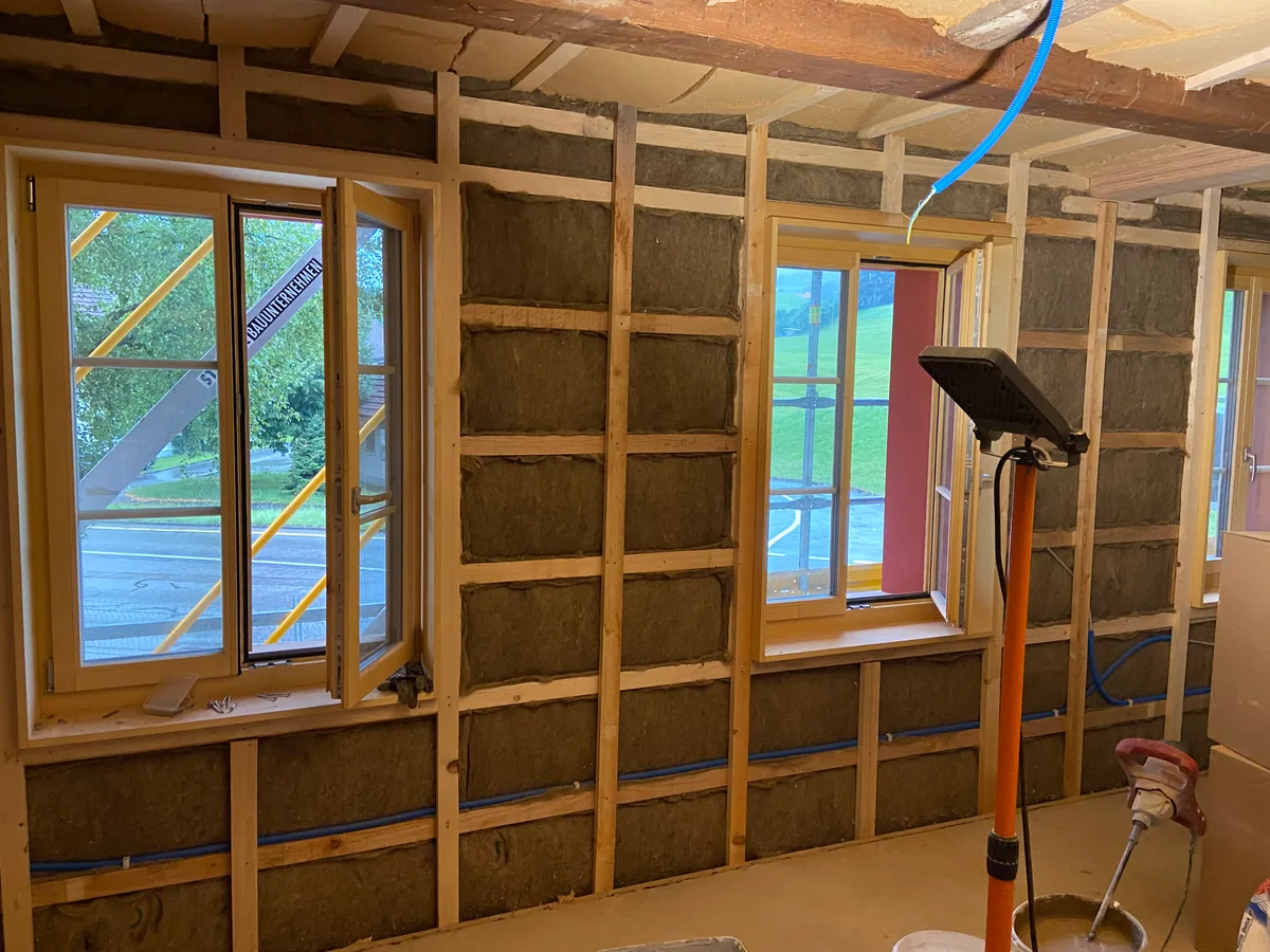 Das gesamte Holzwerk inklusive der Fensterrahmen besteht aus Mondholz. Als Isolation dienen Holzwolle, Schafwolle und Hanf. Isolationsarbeiten im Innenbereich eines Hauses.